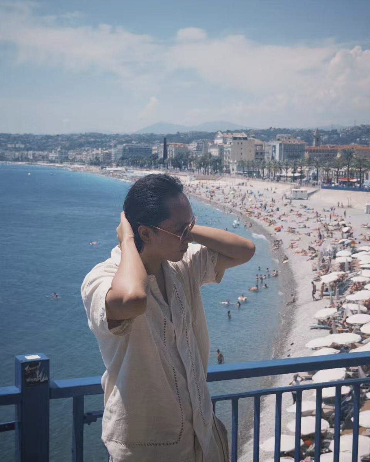 Shay at a blue railing overlooking the sea and the Promenade des Anglais in Nice.
